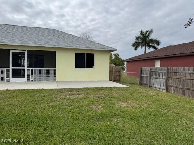 back of house featuring roof with shingles, a patio, stucco siding, a lawn, and a fenced backyard