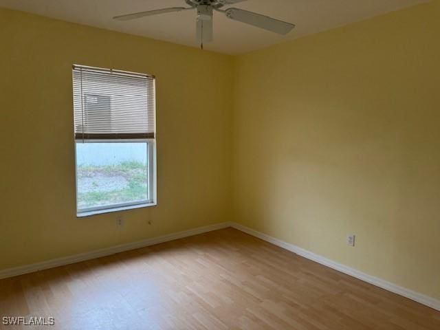 unfurnished room with wood finished floors, a ceiling fan, and baseboards