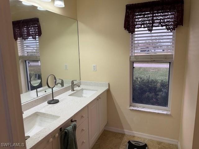 full bath with double vanity, tile patterned flooring, baseboards, and a sink