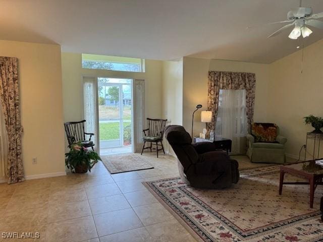 tiled living room with ceiling fan, lofted ceiling, and baseboards