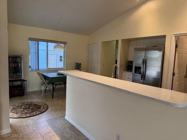 kitchen with a sink, baseboards, vaulted ceiling, light countertops, and appliances with stainless steel finishes