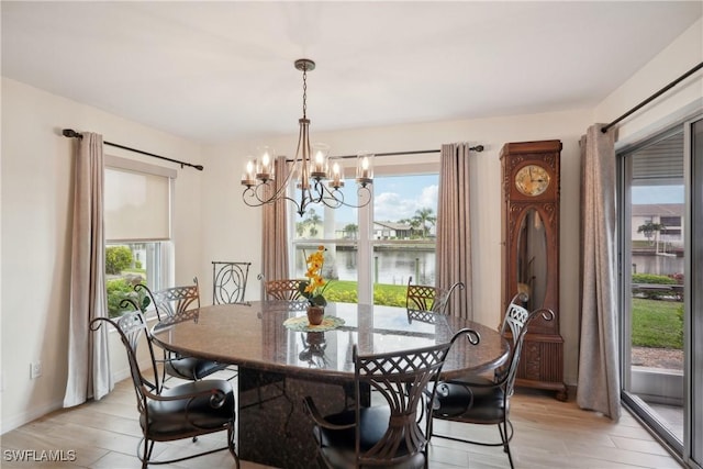 dining space with a water view, light hardwood / wood-style floors, and an inviting chandelier