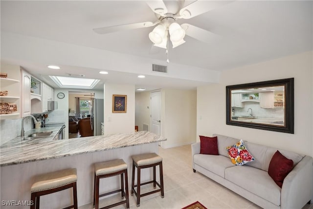 kitchen featuring a breakfast bar, white cabinetry, kitchen peninsula, and sink