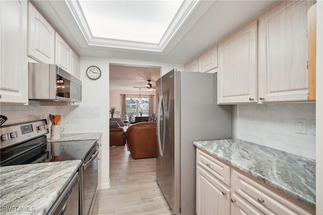 kitchen featuring decorative backsplash, ceiling fan, stainless steel appliances, and light stone counters