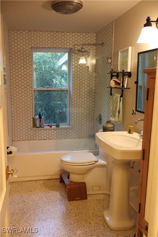 bathroom with toilet and tiled shower / bath