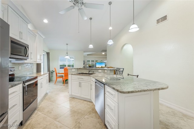 kitchen with a large island with sink, appliances with stainless steel finishes, white cabinetry, sink, and hanging light fixtures