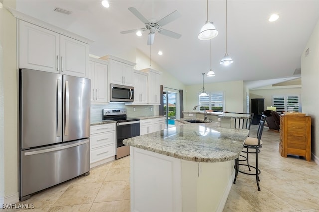 kitchen featuring appliances with stainless steel finishes, a kitchen island, white cabinetry, sink, and backsplash