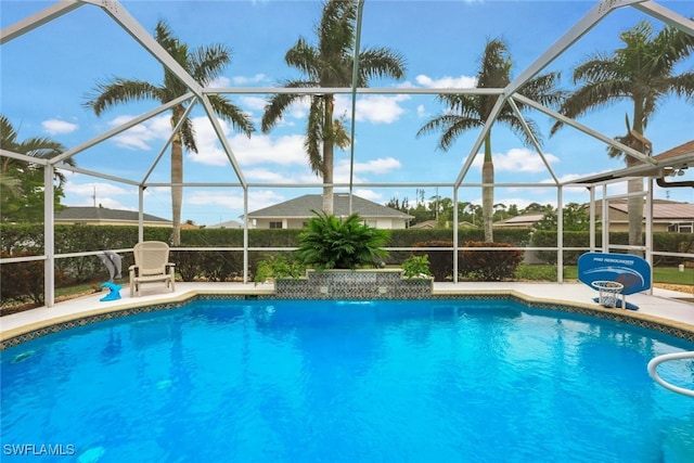 view of pool with glass enclosure and a patio area