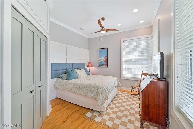 bedroom featuring ceiling fan, light hardwood / wood-style floors, a closet, and crown molding