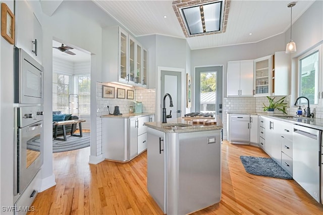 kitchen with appliances with stainless steel finishes, a kitchen island, white cabinetry, sink, and wooden ceiling