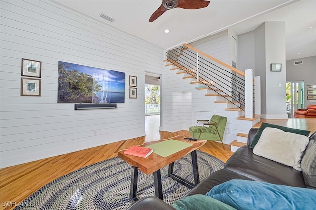 living room featuring ceiling fan, wooden walls, and wood-type flooring