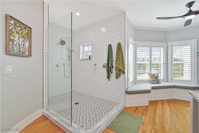 bathroom featuring a tile shower, hardwood / wood-style flooring, ceiling fan, and crown molding