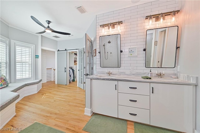 bathroom featuring ceiling fan, wood-type flooring, vanity, and tasteful backsplash