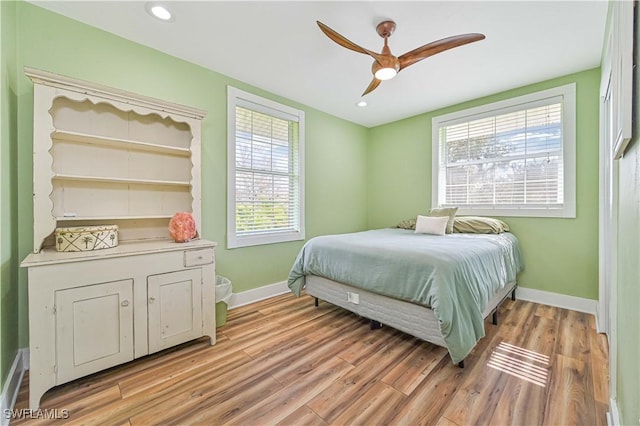 bedroom with multiple windows, ceiling fan, and light hardwood / wood-style floors