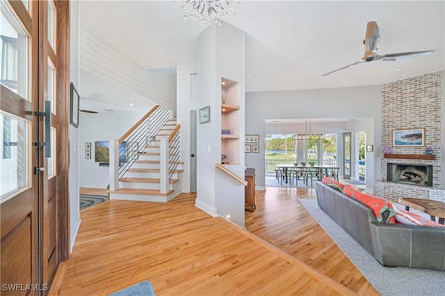 entrance foyer with a fireplace, hardwood / wood-style flooring, and ceiling fan with notable chandelier