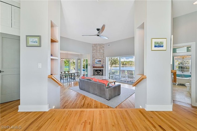 living room with ceiling fan, a brick fireplace, and hardwood / wood-style floors