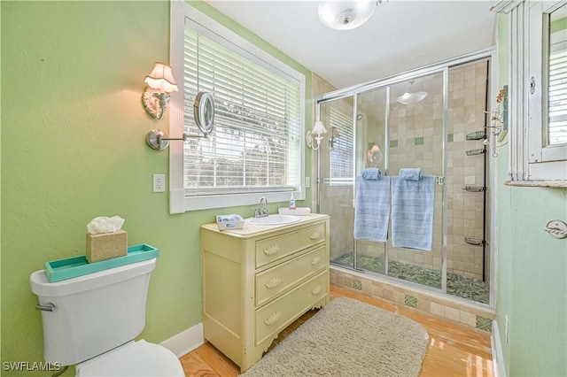 bathroom featuring hardwood / wood-style floors, toilet, walk in shower, and vanity