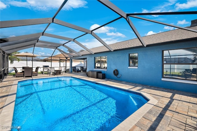 view of swimming pool featuring glass enclosure and a patio area