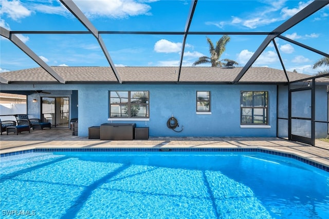 view of swimming pool featuring glass enclosure, ceiling fan, and a patio area