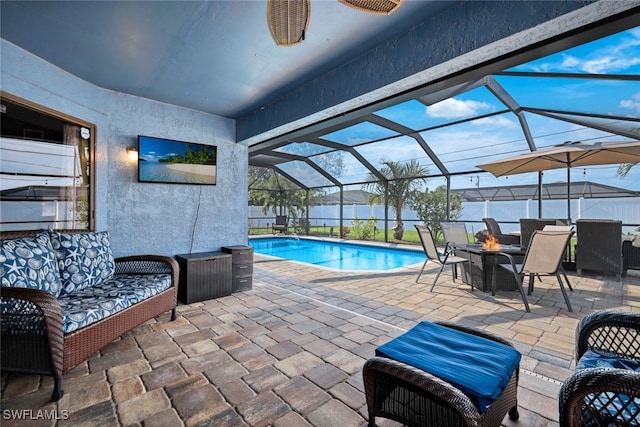 view of swimming pool featuring a patio area, a lanai, and an outdoor living space with a fire pit