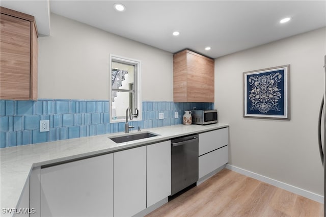 kitchen with tasteful backsplash, sink, light hardwood / wood-style flooring, stainless steel appliances, and white cabinets