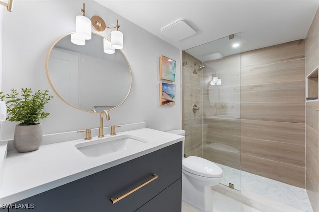 bathroom with toilet, a tile shower, and vanity