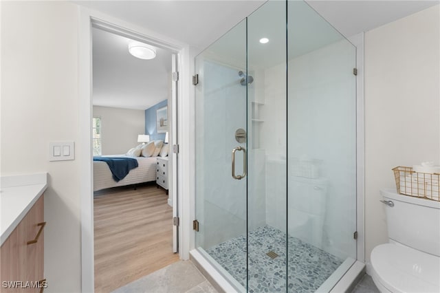 bathroom with toilet, a shower with shower door, hardwood / wood-style flooring, and vanity