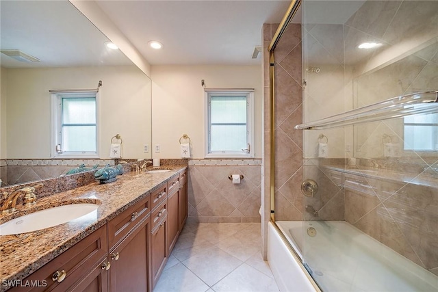 bathroom with tile walls, shower / bath combination with glass door, a wealth of natural light, and vanity