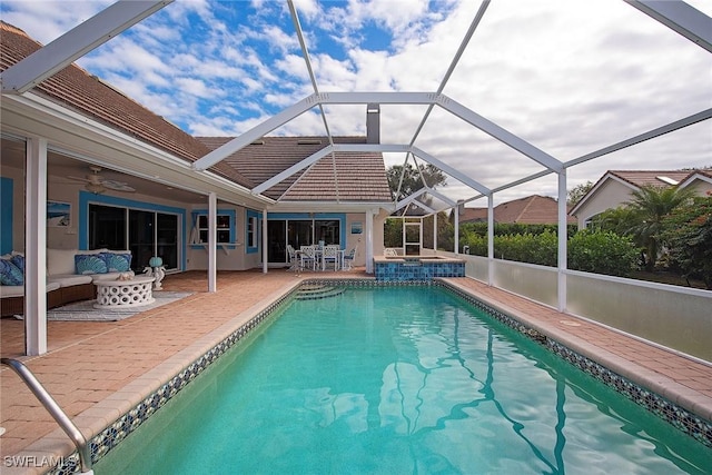 view of swimming pool with ceiling fan, a lanai, an outdoor living space, and a patio