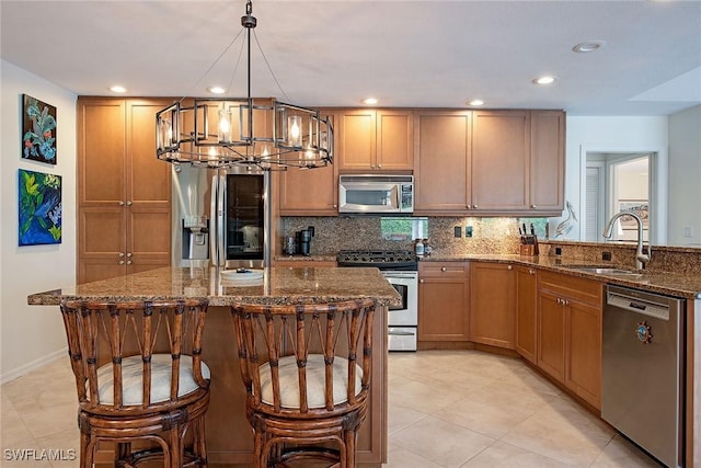 kitchen with tasteful backsplash, dark stone counters, sink, decorative light fixtures, and stainless steel appliances