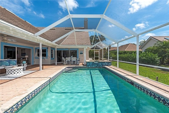 view of swimming pool with ceiling fan, a lanai, outdoor lounge area, a pool with connected hot tub, and a patio area