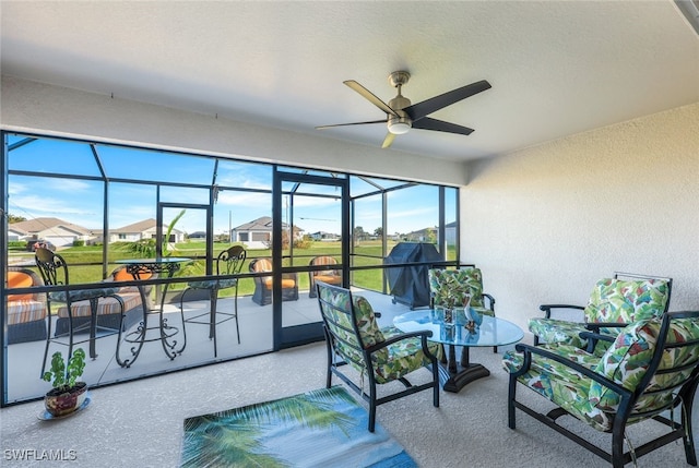 sunroom featuring ceiling fan and a residential view