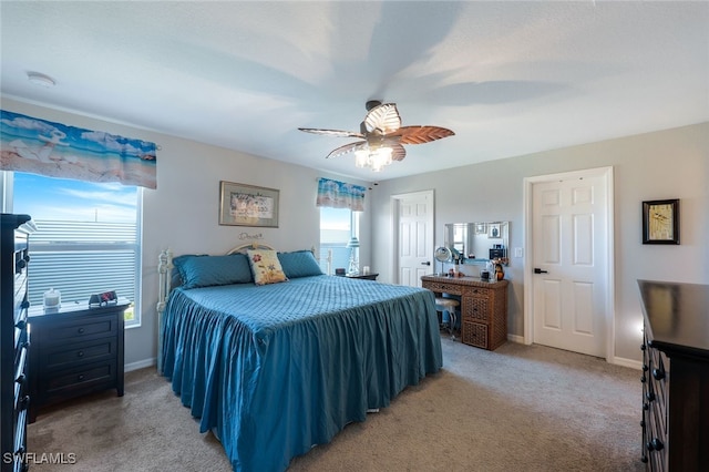 bedroom featuring a closet, light colored carpet, ceiling fan, and baseboards