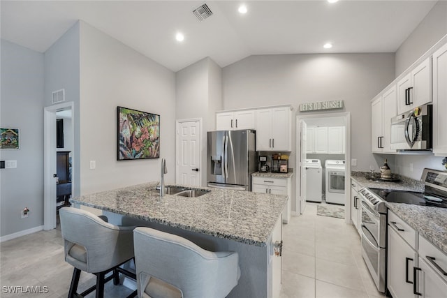 kitchen featuring visible vents, appliances with stainless steel finishes, washer and dryer, white cabinetry, and a sink