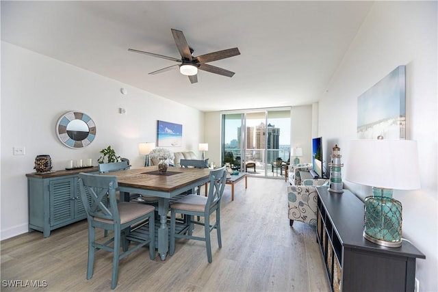 dining area featuring ceiling fan, light hardwood / wood-style floors, and a wall of windows