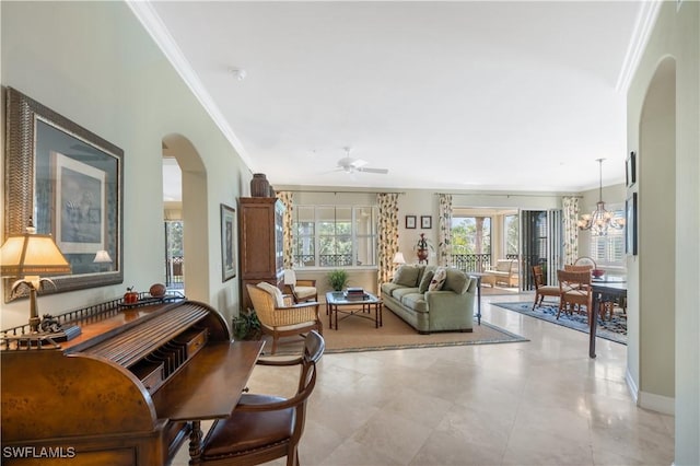 living room featuring arched walkways, ornamental molding, ceiling fan with notable chandelier, and baseboards