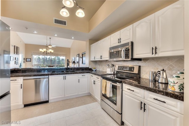 kitchen featuring stainless steel appliances, sink, white cabinets, a chandelier, and lofted ceiling