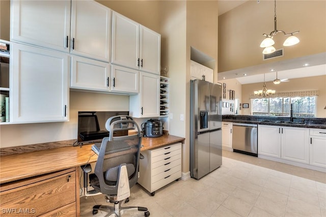 kitchen featuring dark stone counters, an inviting chandelier, white cabinets, hanging light fixtures, and stainless steel appliances