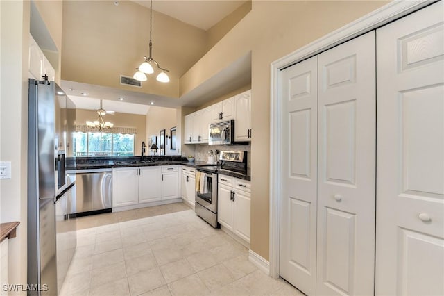 kitchen with appliances with stainless steel finishes, a notable chandelier, white cabinets, hanging light fixtures, and light tile patterned flooring