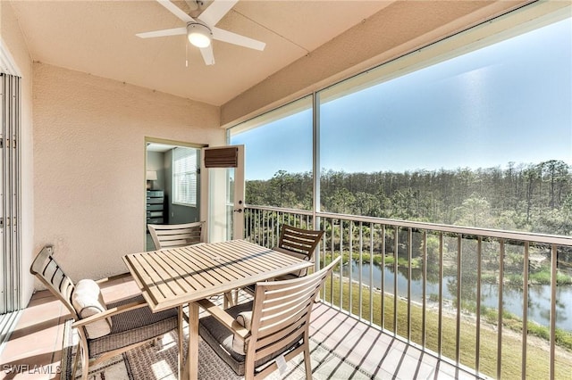 sunroom with ceiling fan and a water view