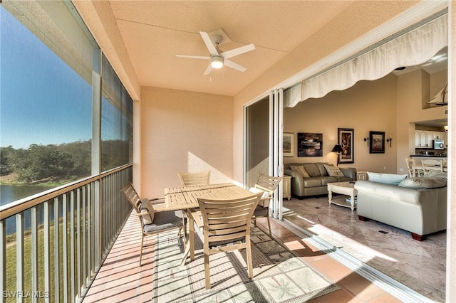 sunroom / solarium with ceiling fan and a water view