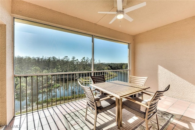 sunroom featuring a water view and ceiling fan