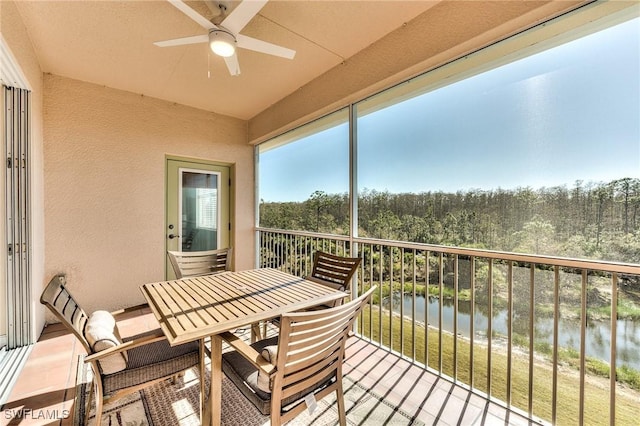 sunroom with ceiling fan and a water view