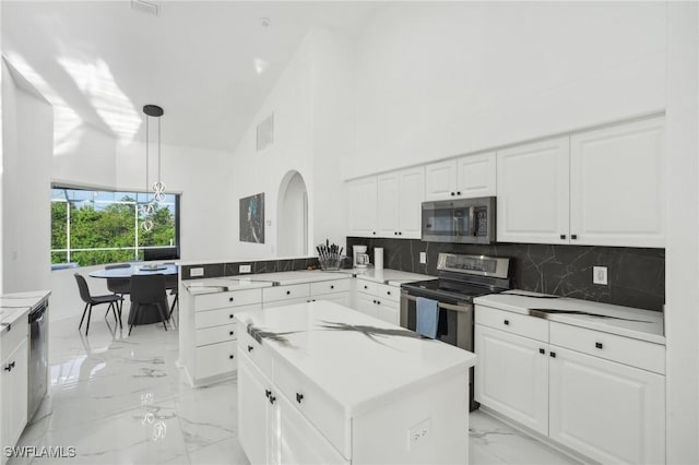 kitchen with pendant lighting, a center island, backsplash, high vaulted ceiling, and appliances with stainless steel finishes