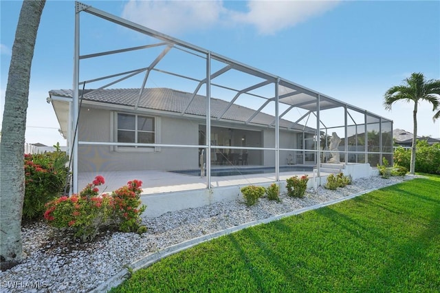 rear view of property with a lanai, a yard, and a patio