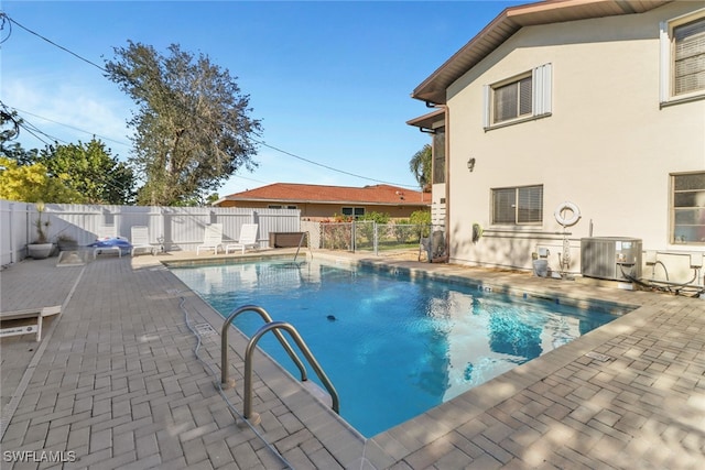 view of swimming pool featuring central air condition unit and a patio area