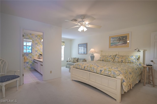 bedroom featuring ensuite bath, ceiling fan, and light colored carpet