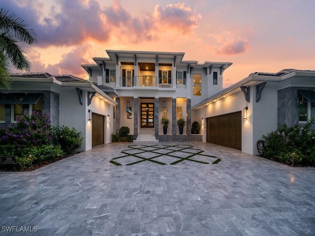 view of front facade featuring a garage, a balcony, and french doors