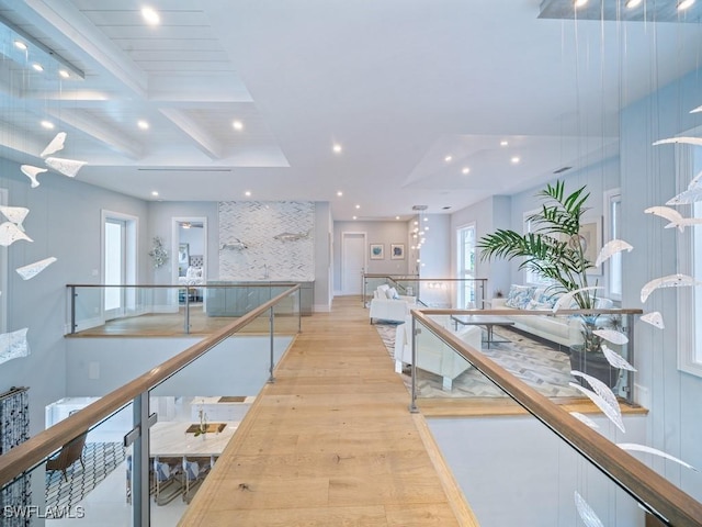 interior space featuring beam ceiling, plenty of natural light, coffered ceiling, and light wood-type flooring