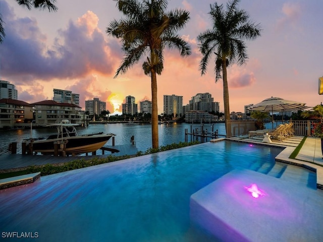 pool at dusk with a water view and a boat dock